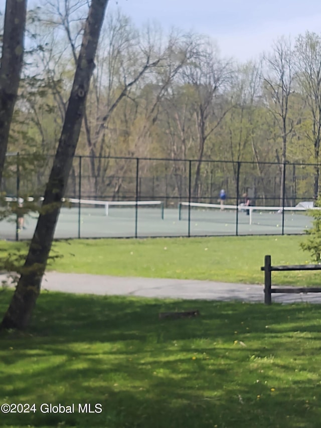 view of sport court featuring fence and a lawn