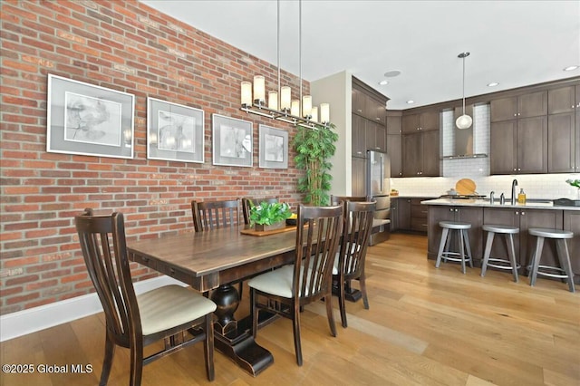 dining area featuring recessed lighting, brick wall, and light wood-style floors