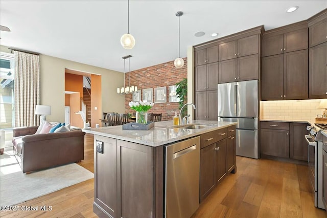 kitchen featuring dark brown cabinetry, stainless steel appliances, light wood-style floors, and a sink