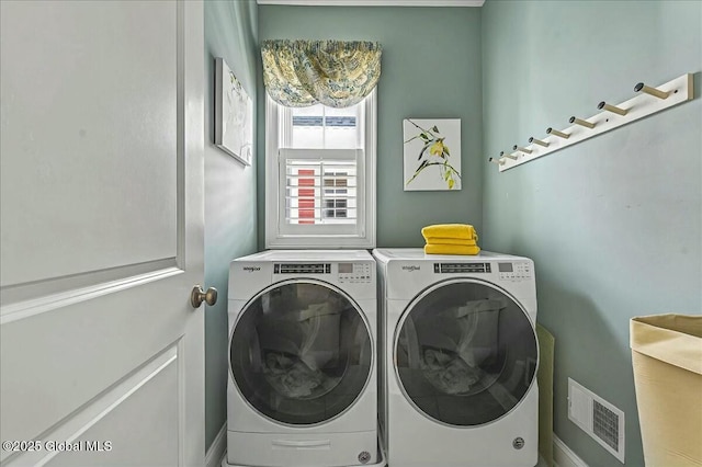 clothes washing area with visible vents, separate washer and dryer, and laundry area