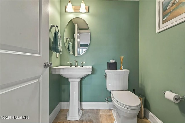 bathroom featuring tile patterned floors, toilet, baseboards, and a sink