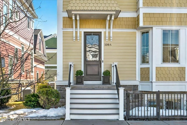 entrance to property with stone siding and fence