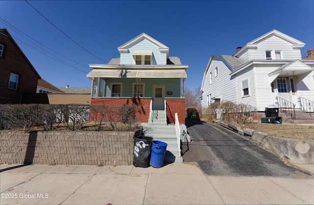 view of front of home featuring a porch, fence, and brick siding