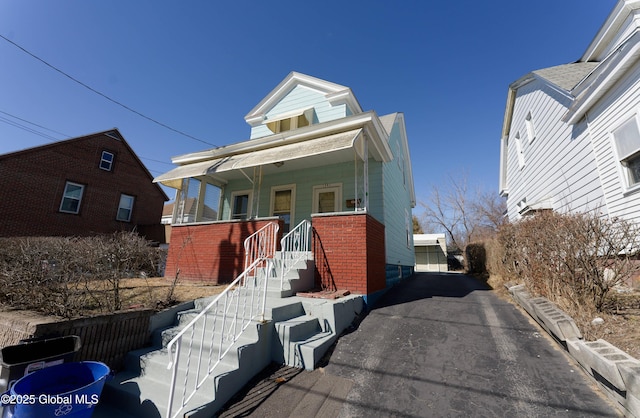 view of front of house featuring brick siding and a porch