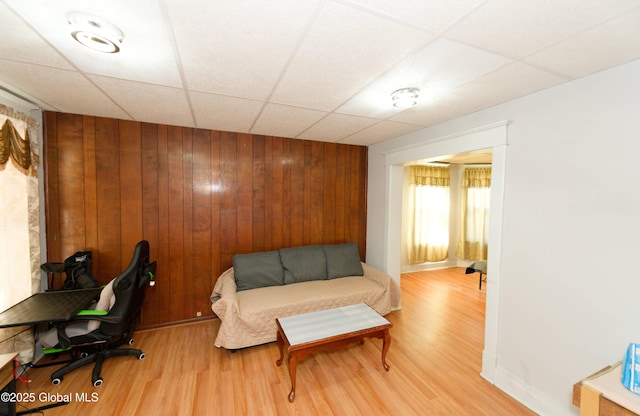 office area featuring wooden walls, a drop ceiling, and wood finished floors