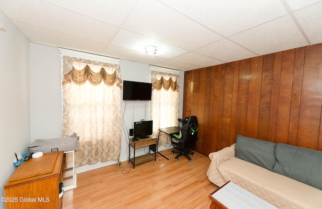 home office featuring wooden walls, a paneled ceiling, and wood finished floors