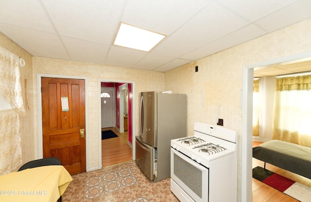 kitchen featuring light wood finished floors, white range with gas cooktop, freestanding refrigerator, and a paneled ceiling