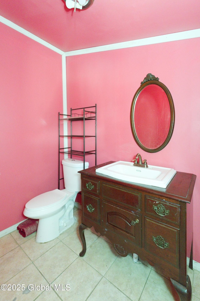 half bath featuring tile patterned flooring, toilet, vanity, and baseboards