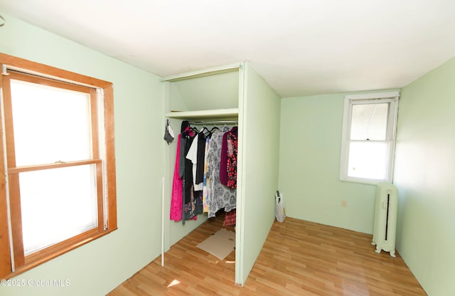 unfurnished bedroom featuring light wood-type flooring, radiator, and a closet