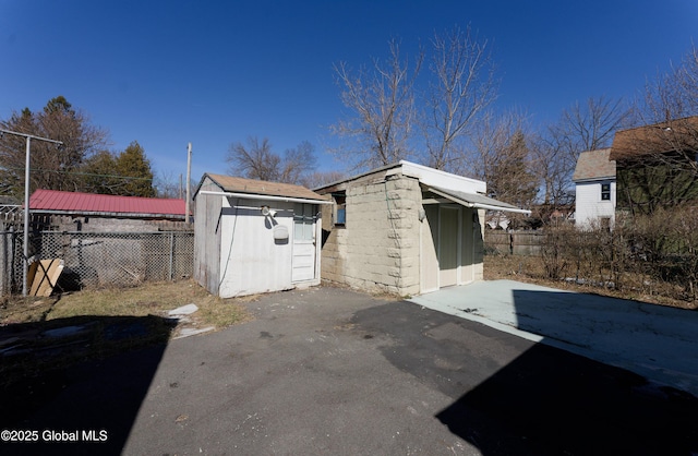 exterior space with concrete block siding, a fenced backyard, an outbuilding, and a shed