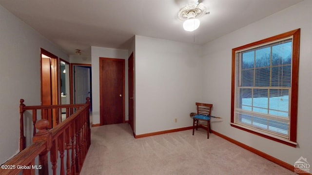 interior space featuring light carpet, an upstairs landing, and baseboards