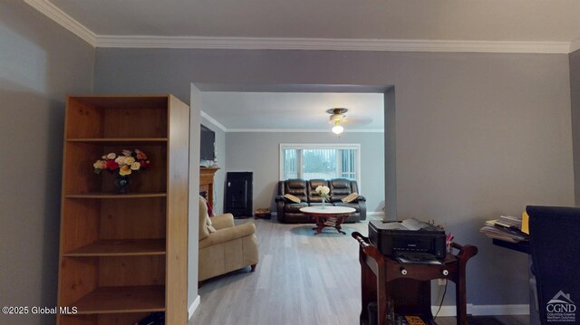 interior space featuring baseboards, a fireplace, ornamental molding, and wood finished floors