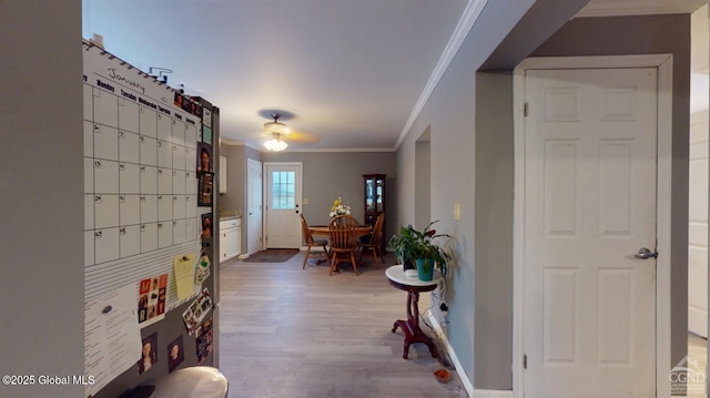 interior space with ornamental molding, light wood-style flooring, and baseboards