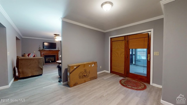 foyer entrance with ornamental molding, a fireplace, baseboards, and wood finished floors