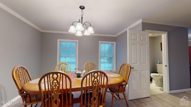 dining space with ornamental molding, a chandelier, light wood-style flooring, and baseboards