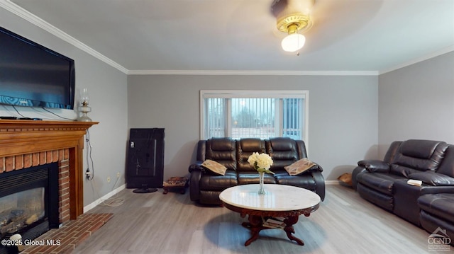 living room featuring a brick fireplace, baseboards, crown molding, and wood finished floors