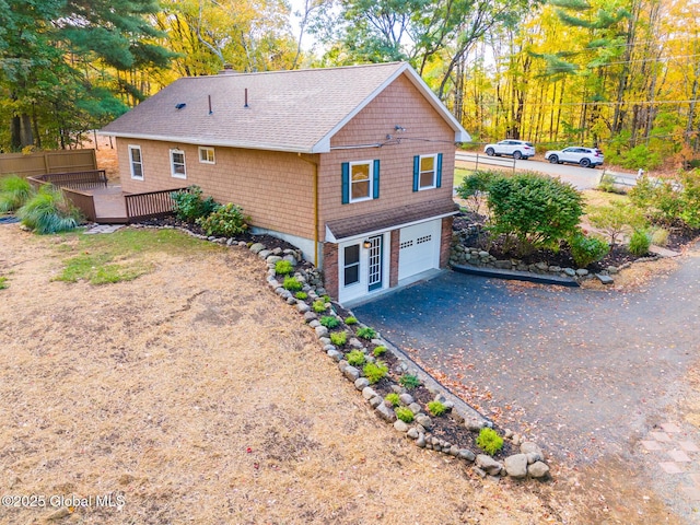 view of front of property featuring a garage, driveway, a deck, and fence