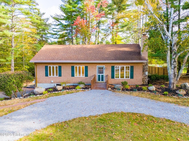 single story home featuring roof with shingles, a chimney, gravel driveway, and fence