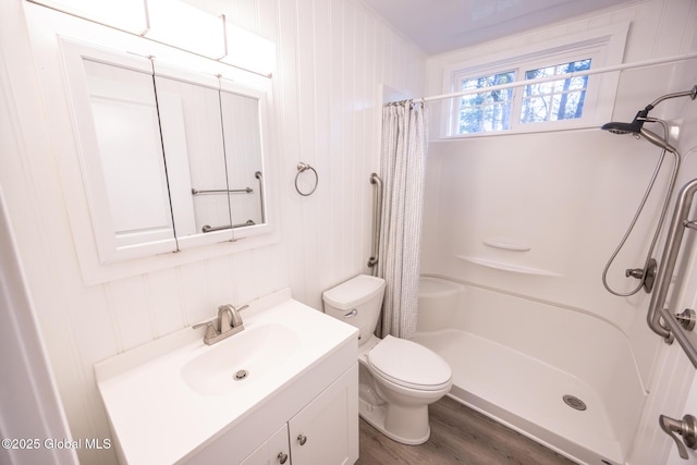 bathroom with toilet, curtained shower, wood finished floors, and vanity