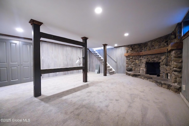 finished below grade area with stairs, carpet floors, a stone fireplace, and recessed lighting