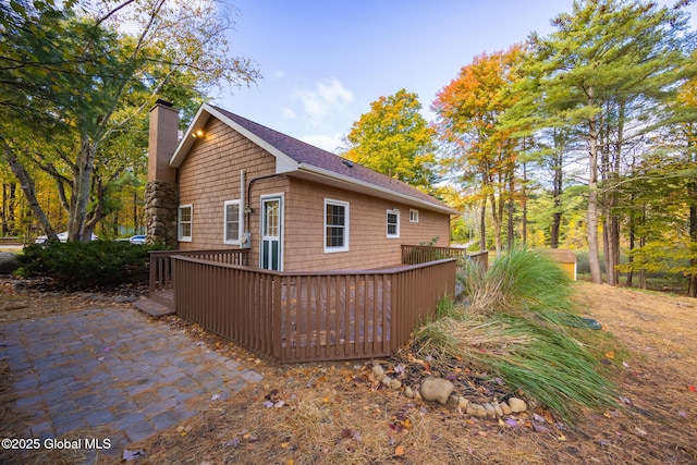 back of property featuring a patio area, a chimney, and a wooden deck