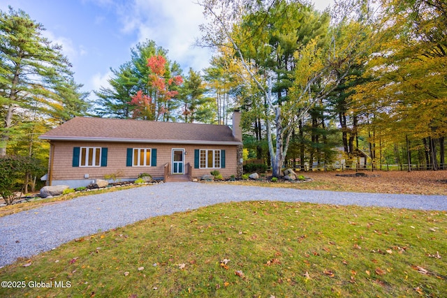 view of front of home with driveway, a chimney, and a front lawn