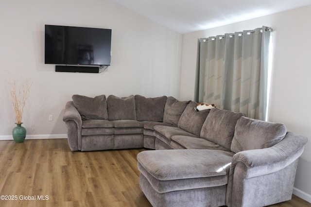 living area with lofted ceiling, wood finished floors, and baseboards