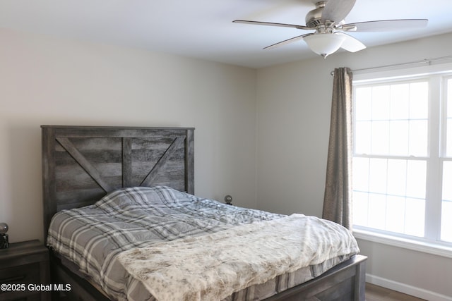 bedroom featuring multiple windows, baseboards, and ceiling fan