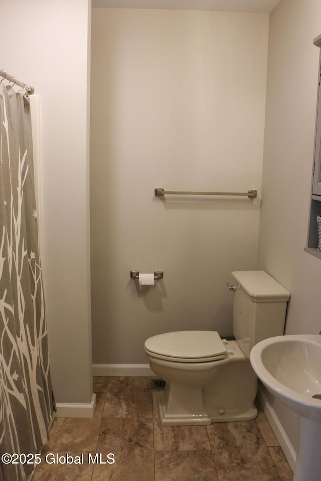 full bathroom with a sink, a shower with curtain, baseboards, and toilet