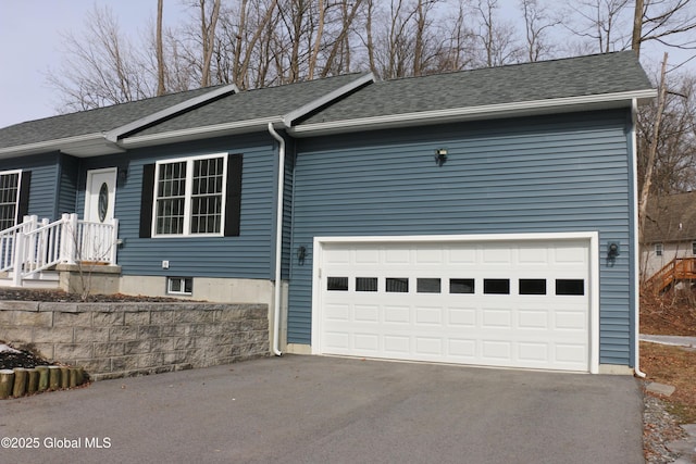 single story home featuring driveway, a shingled roof, and a garage