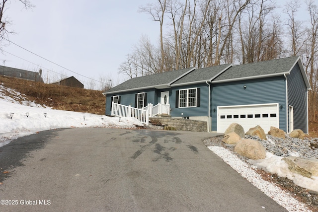 ranch-style house with aphalt driveway, a shingled roof, and a garage