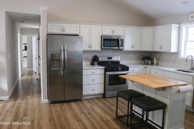 kitchen with a sink, butcher block counters, white cabinetry, and stainless steel appliances