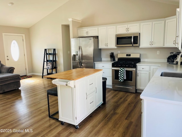 kitchen with appliances with stainless steel finishes, white cabinetry, and vaulted ceiling