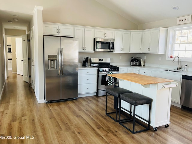 kitchen with wooden counters, stainless steel appliances, light wood-style floors, white cabinetry, and a sink