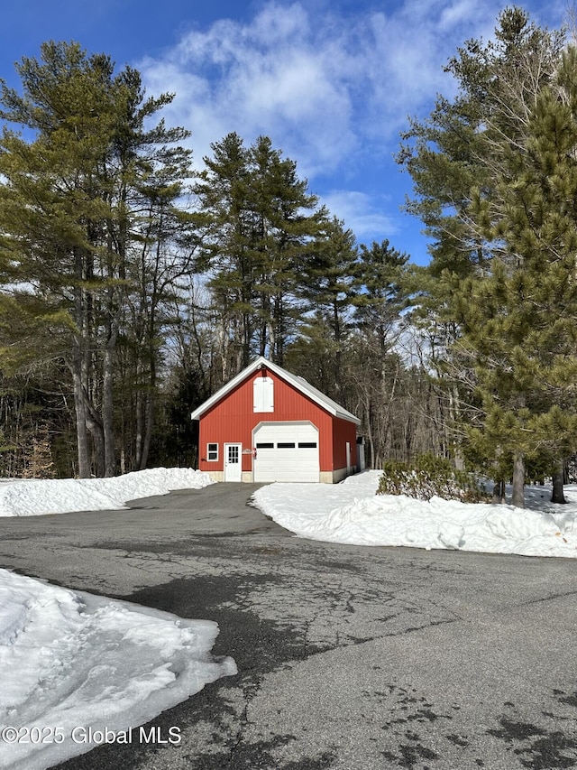 exterior space featuring driveway, a detached garage, and an outdoor structure