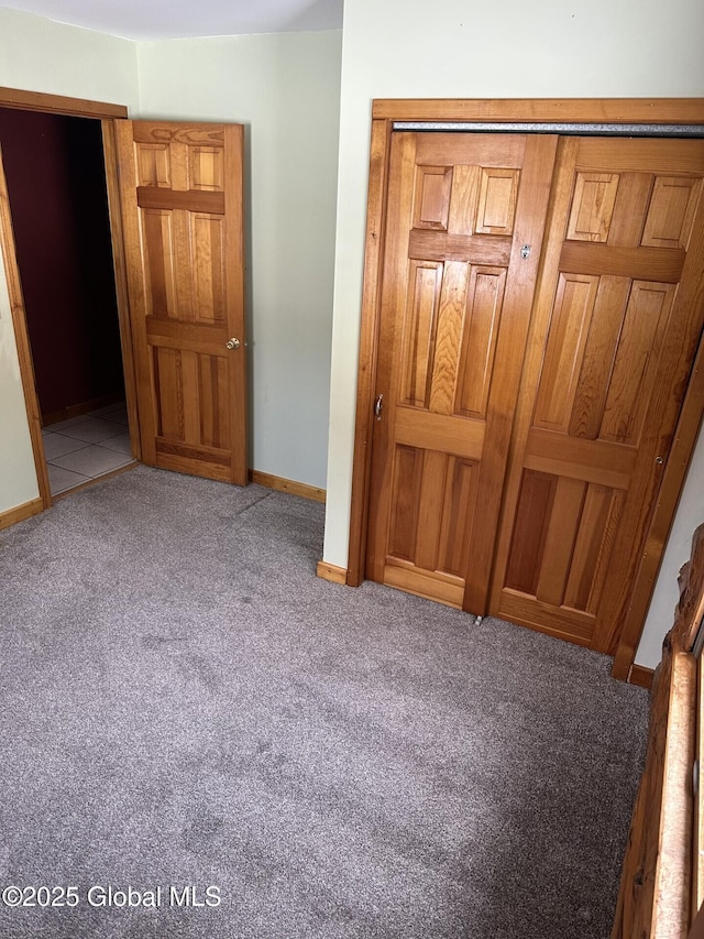 unfurnished bedroom featuring carpet, baseboards, and a closet