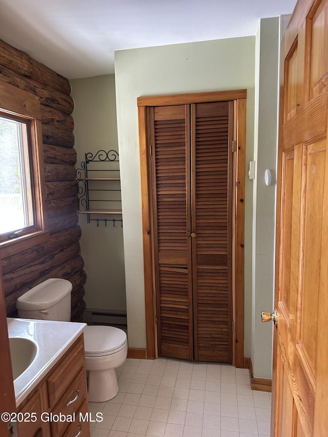 bathroom featuring log walls, a baseboard radiator, a closet, toilet, and vanity