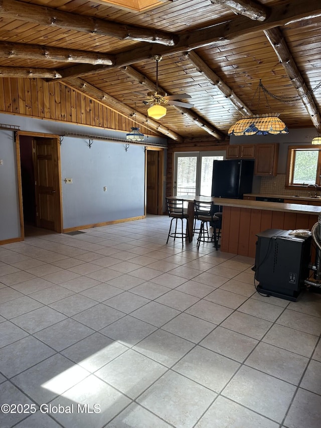 kitchen featuring vaulted ceiling with beams, light tile patterned floors, freestanding refrigerator, wood ceiling, and a peninsula