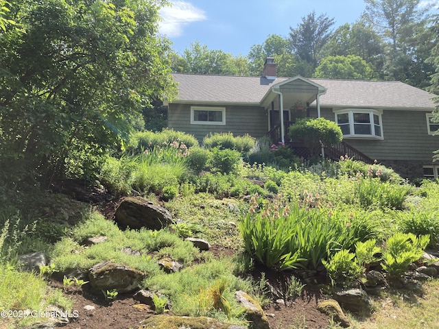 single story home featuring a chimney and a shingled roof