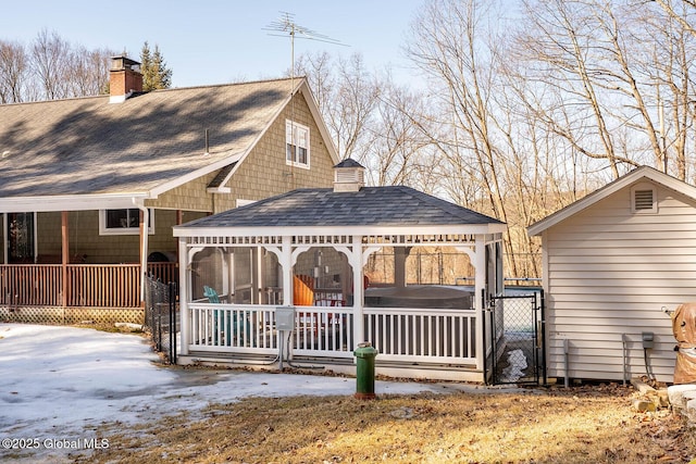 rear view of property featuring a porch, a gate, roof with shingles, and a chimney