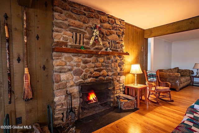 living room with a fireplace, beam ceiling, and wood finished floors