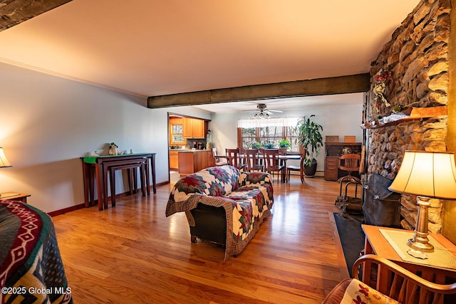 living area featuring light wood-style floors, baseboards, and ceiling fan