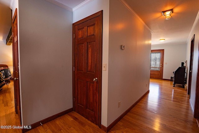 hall featuring baseboards, wood finished floors, and ornamental molding