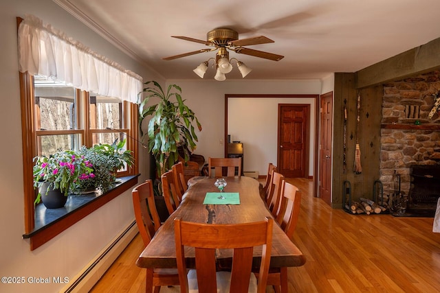 dining space with ceiling fan, light wood-type flooring, baseboard heating, and ornamental molding