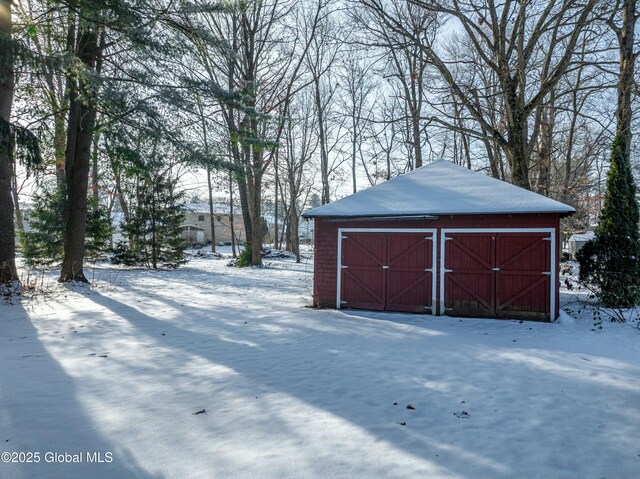 snow covered structure with a storage shed and an outbuilding