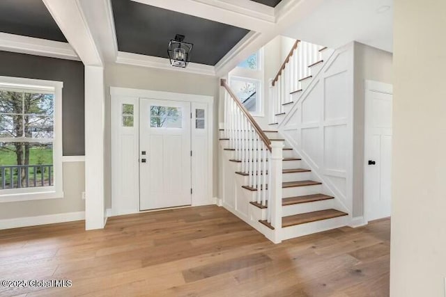 foyer with light wood-type flooring, baseboards, and stairway