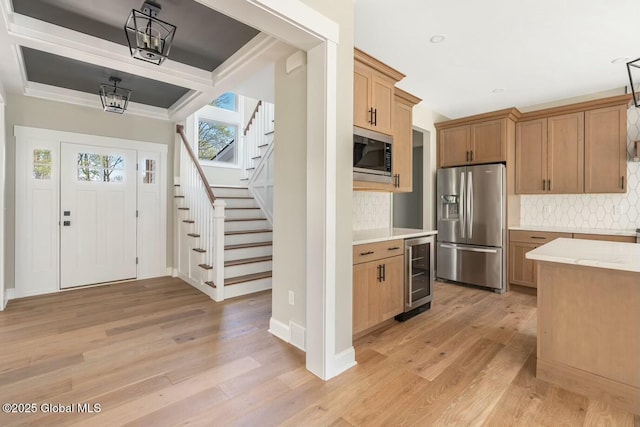 kitchen featuring beverage cooler, baseboards, appliances with stainless steel finishes, light wood-type flooring, and decorative backsplash