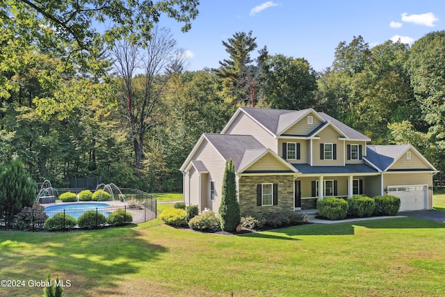 view of front of house featuring a garage, fence, stone siding, a fenced in pool, and a front lawn