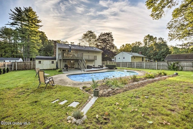 view of pool with an outbuilding, a yard, a storage shed, a fenced backyard, and stairs