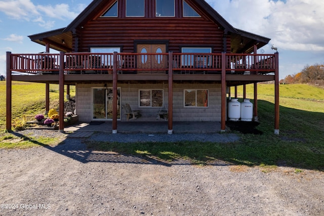 back of house with a yard, a wooden deck, a patio, and log siding